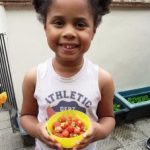 young girl holding a bowl of strawberries
